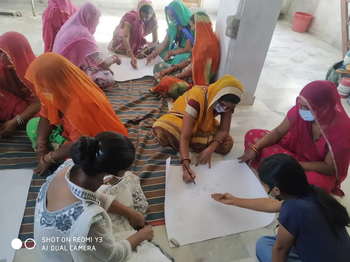 A design sketching session — artisans working through new appliqué patterns on paper.