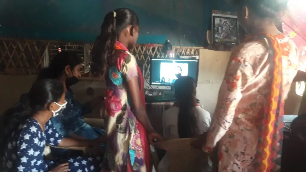 Young women at a digital training session, gathered around a shared screen.