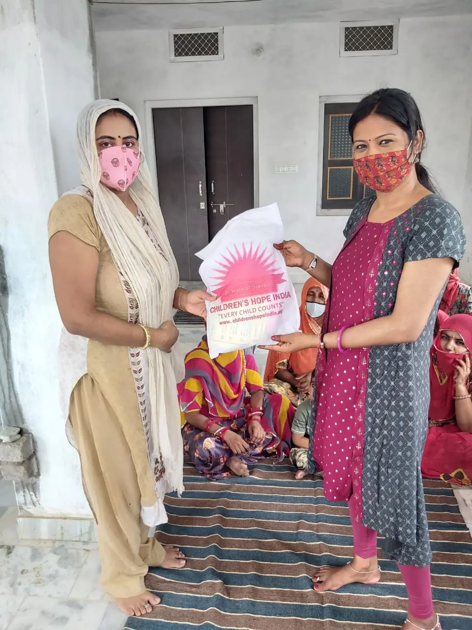 A relief kit handed over as families look on from the courtyard.
