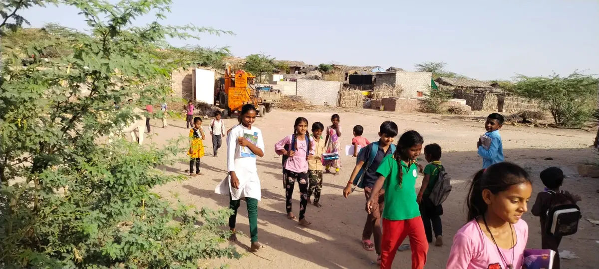 Children walking to the centre together, school bags on their backs.