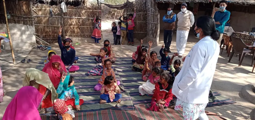 A masked outdoor health education session during the pandemic, led by a UJAS health worker.